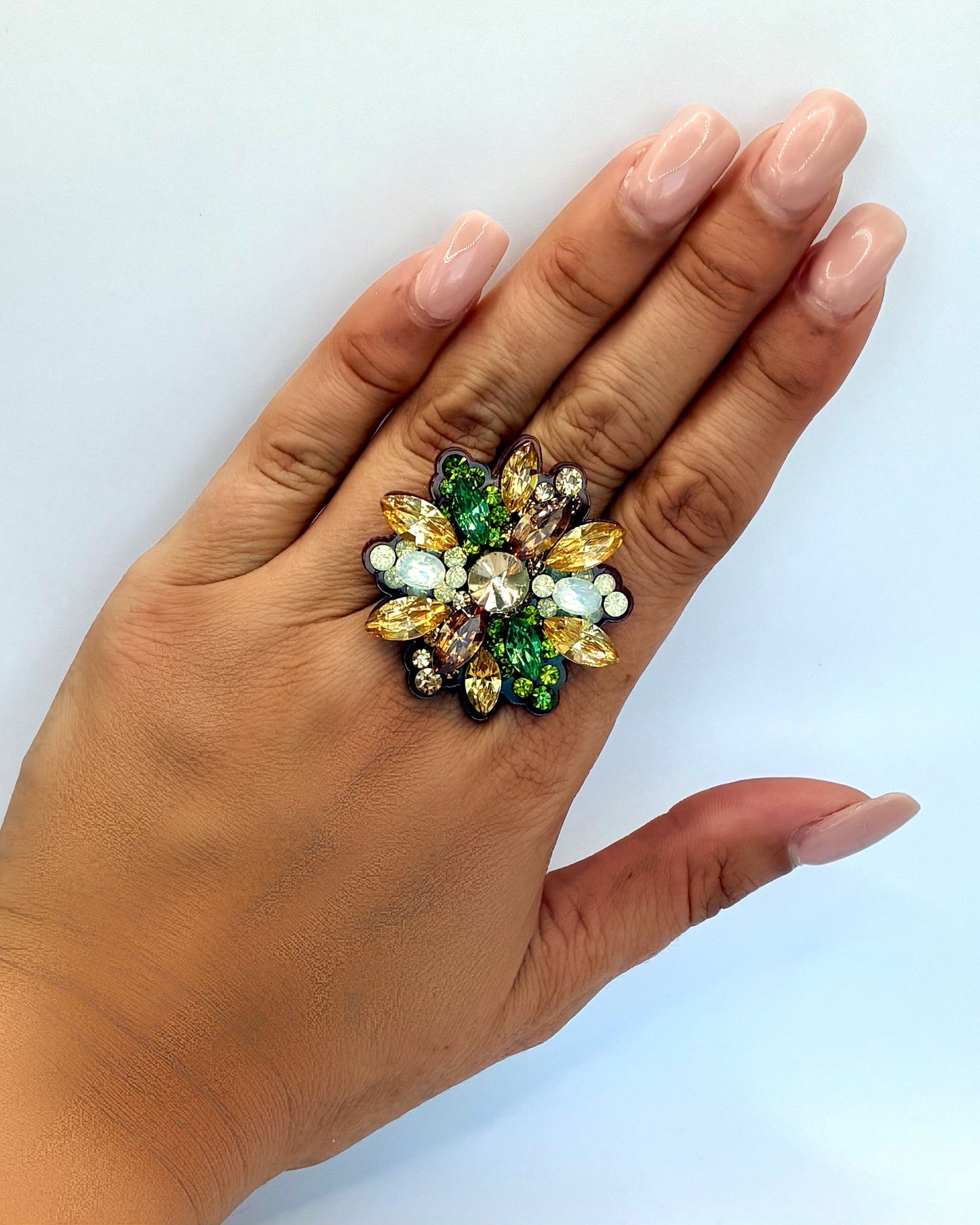 Hand wearing a colorful gemstone ring on a white background