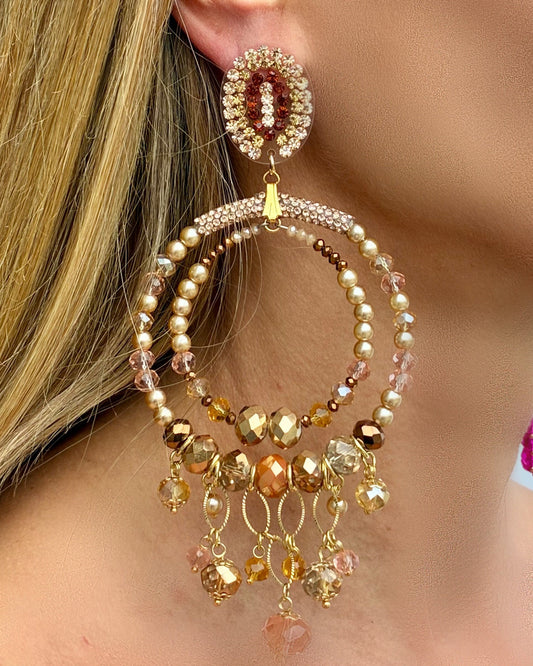Close-up of a person wearing a beaded earring with pearls and crystals.