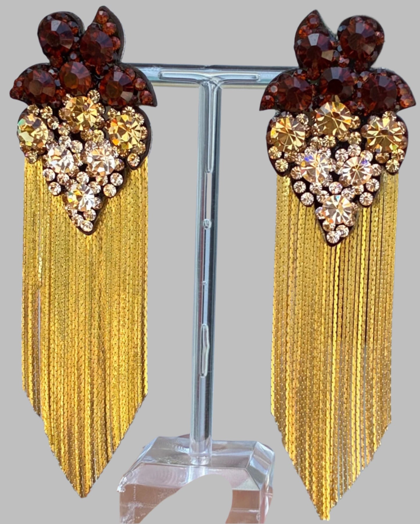 Earrings with gold fringe and gemstone accents on a stand