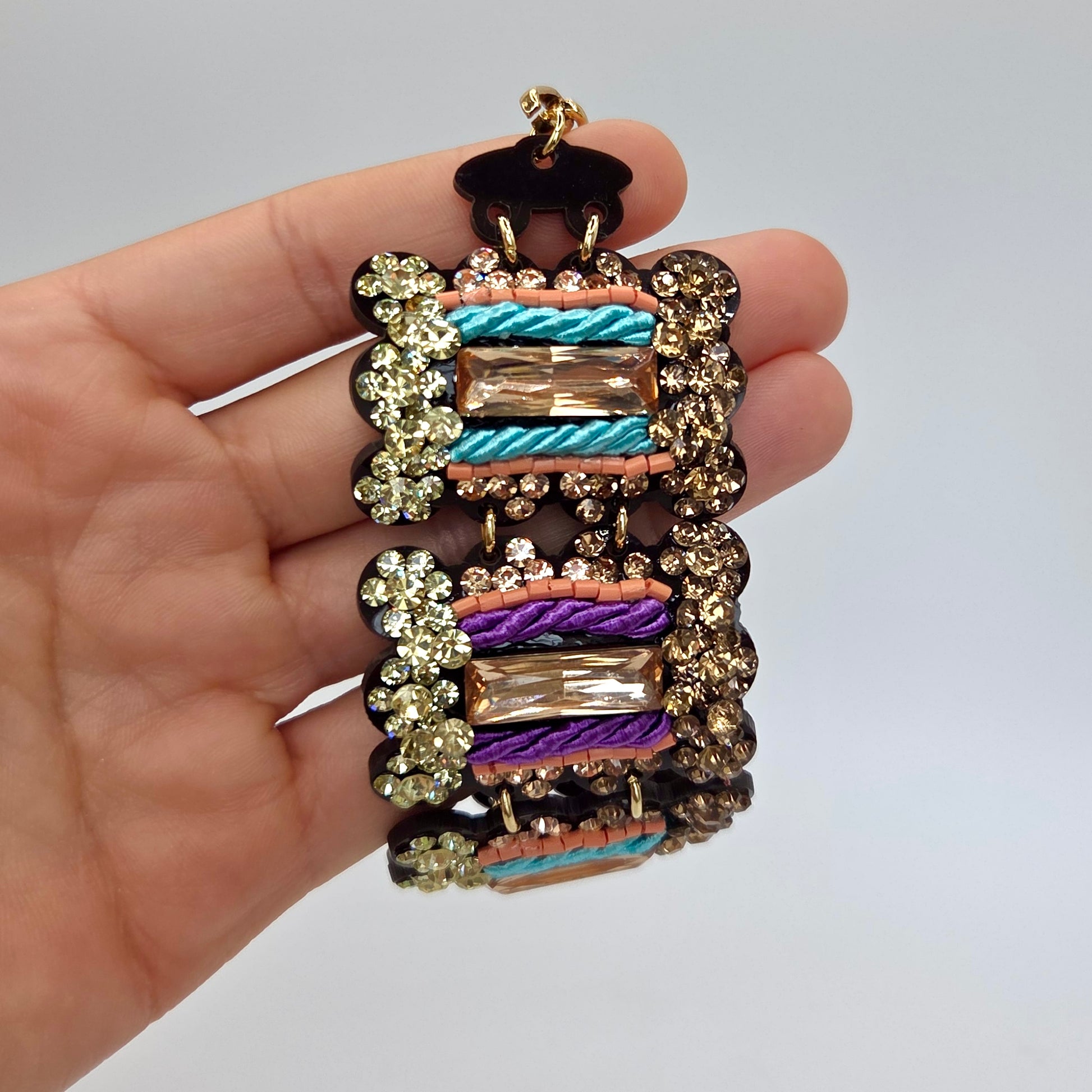 Multicolored beaded bracelet held in a hand against a plain background