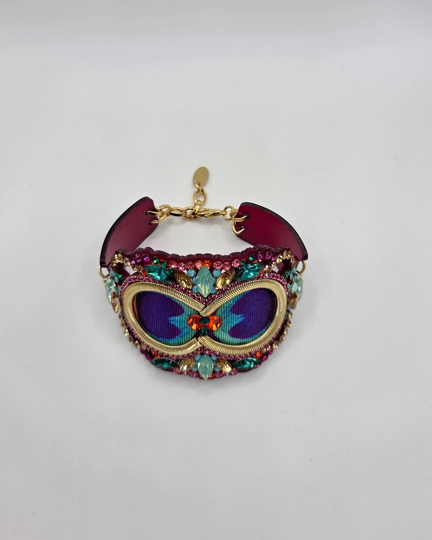 Colorful embroidered bracelet with gemstones on a light gray background