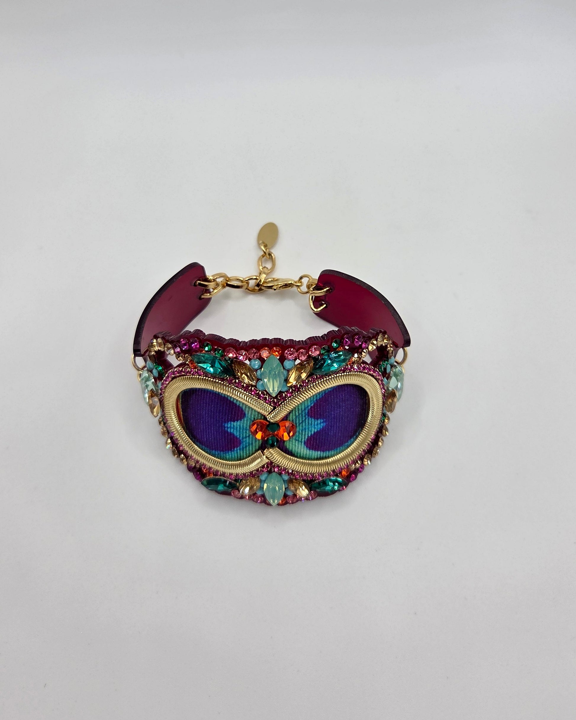 Colorful embroidered bracelet with gemstones on a light gray background