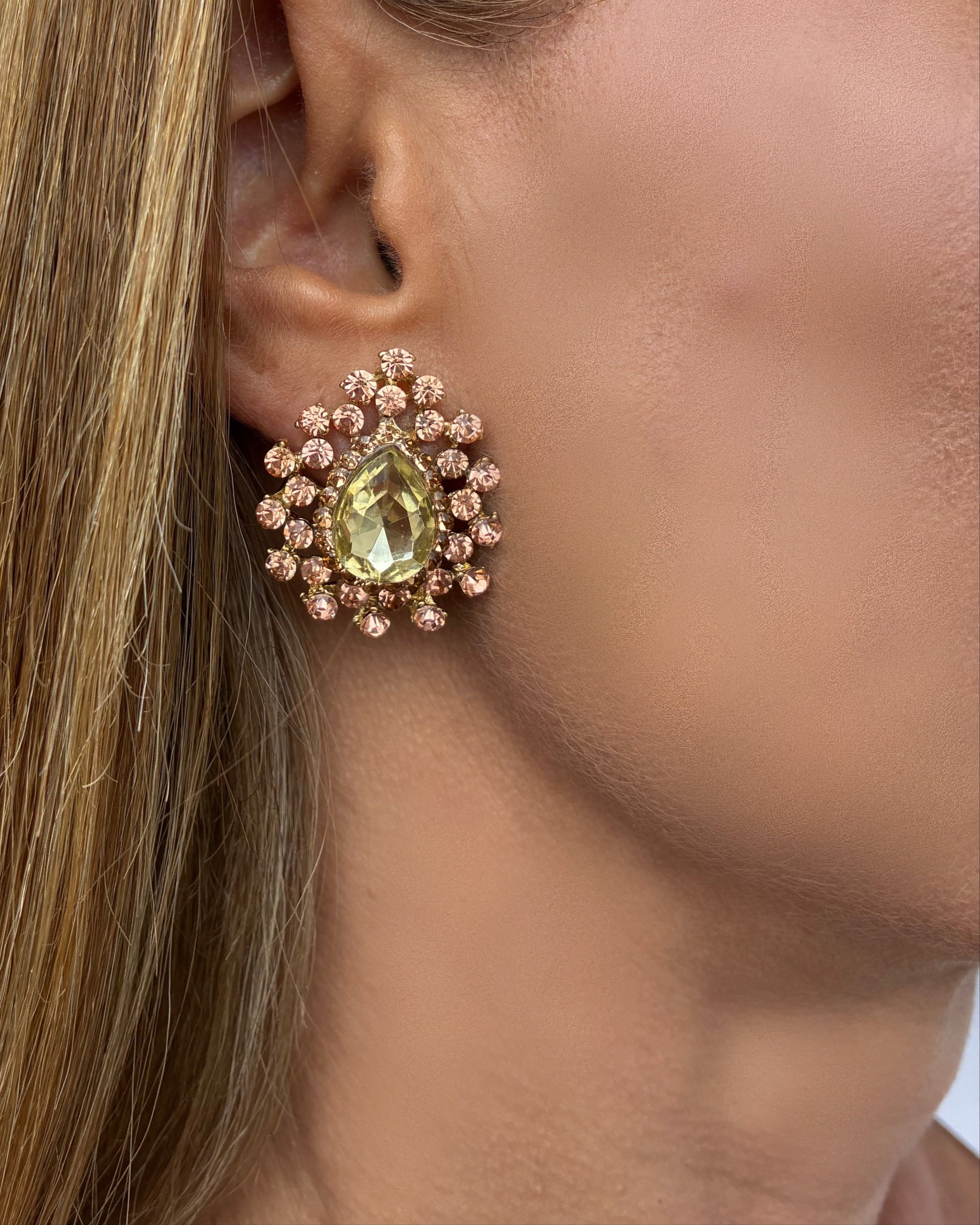 Close-up of a woman wearing a decorative earring with a green gemstone.