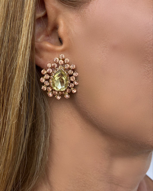 Close-up of a woman wearing a decorative earring with a green gemstone.