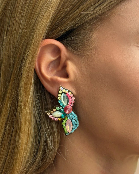 Close-up of a colorful butterfly earring worn by a person.