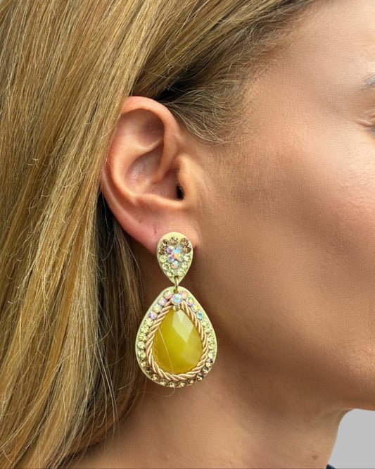Close-up of a woman wearing a gold earring with a yellow stone.