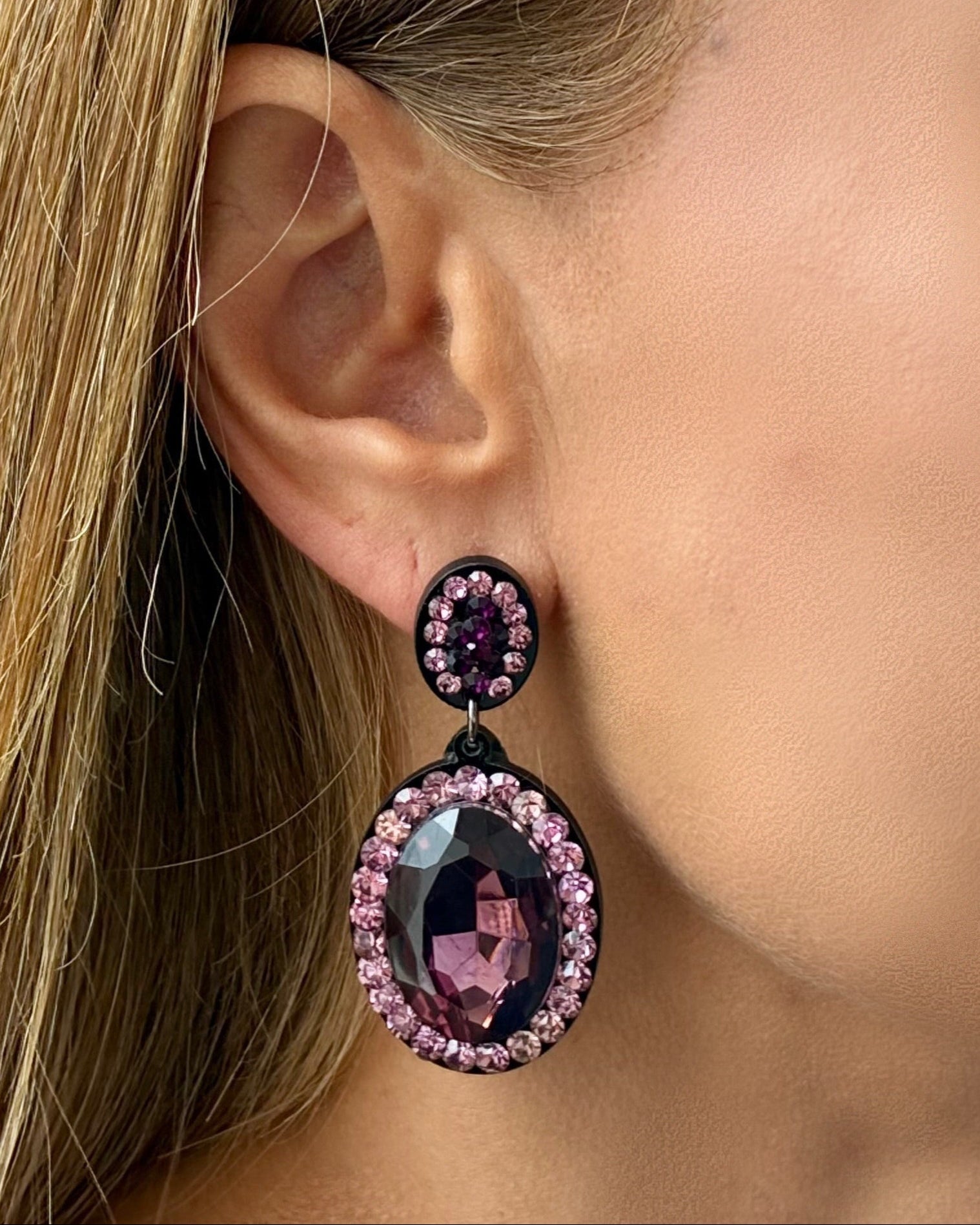 Close-up of a woman wearing purple gemstone earrings.