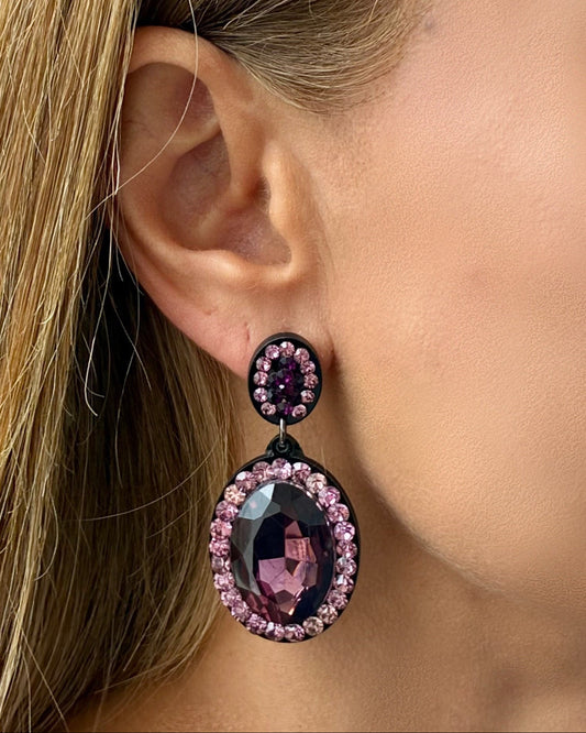Close-up of a woman wearing purple gemstone earrings.