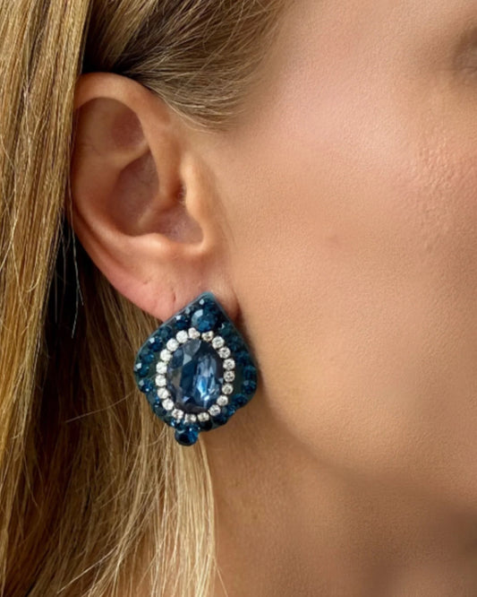 Close-up of a woman wearing blue beaded earrings with a blurred background