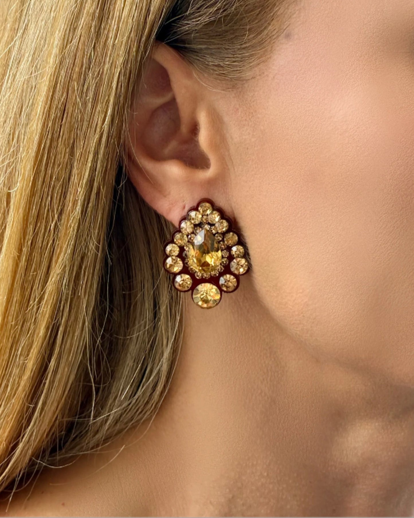Close-up of a person wearing a gold and red earring.