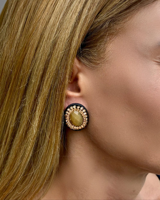 Close-up of a woman wearing a gold earring with a central stone.