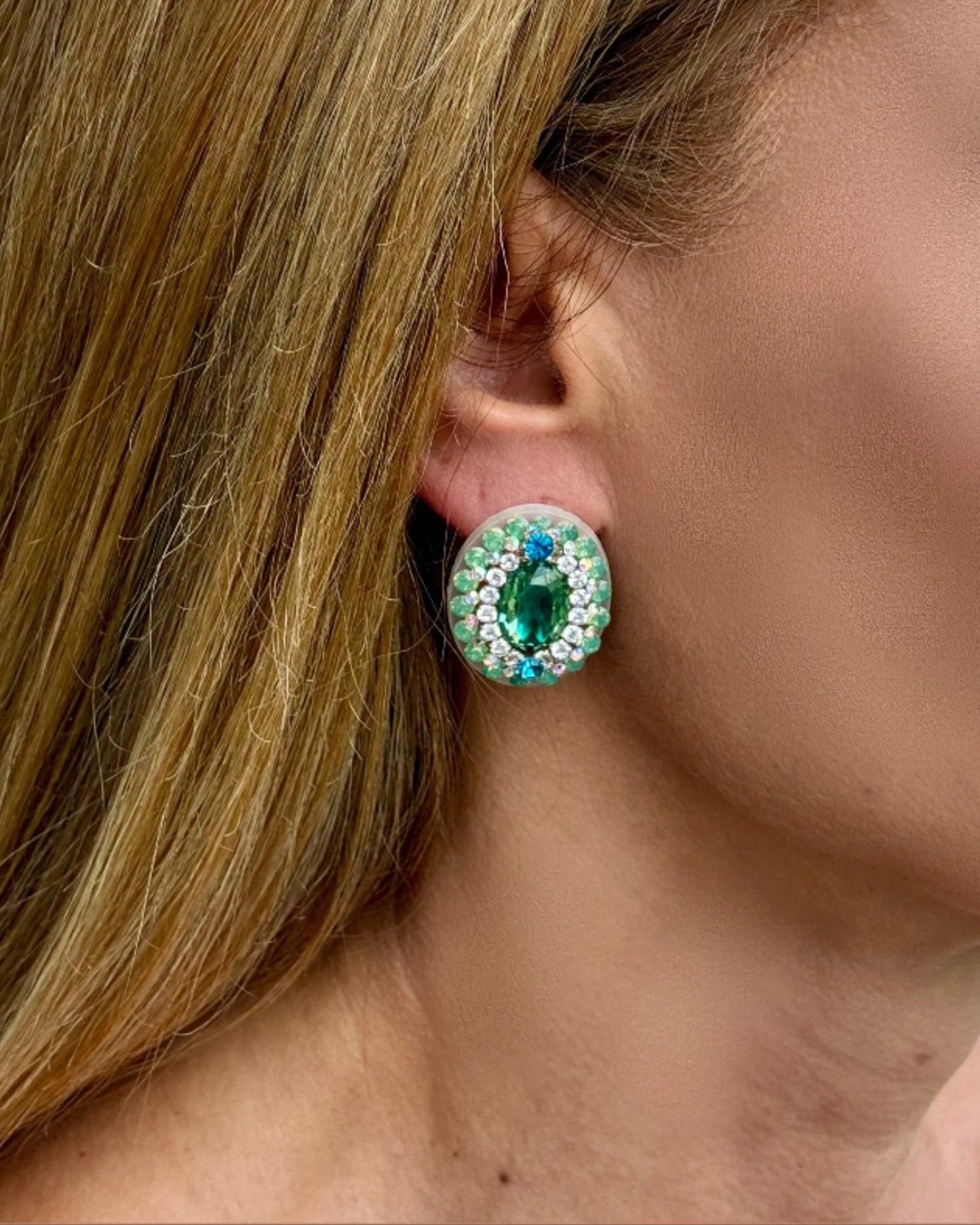 Close-up of a person wearing a green gemstone earring.
