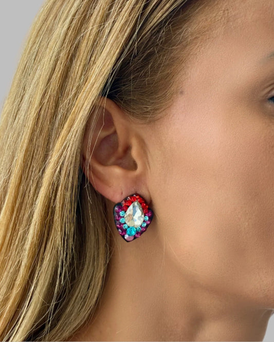 Close-up of a woman wearing colorful gemstone earrings with a neutral background