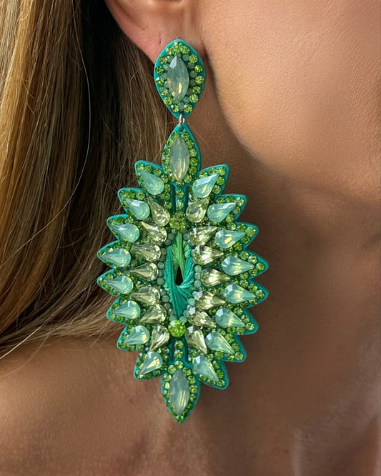 Close-up of a green leaf-shaped earring worn by a person.