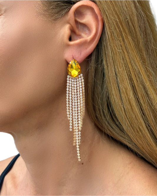 Close-up of a woman wearing a yellow gemstone earring with dangling crystals.