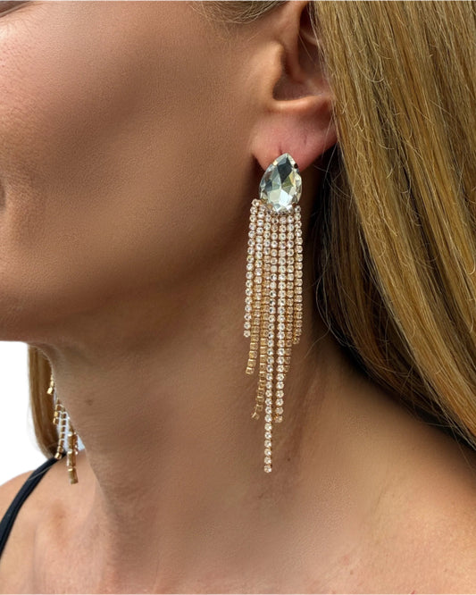 Close-up of a woman wearing a sparkling earring with a clear gemstone.