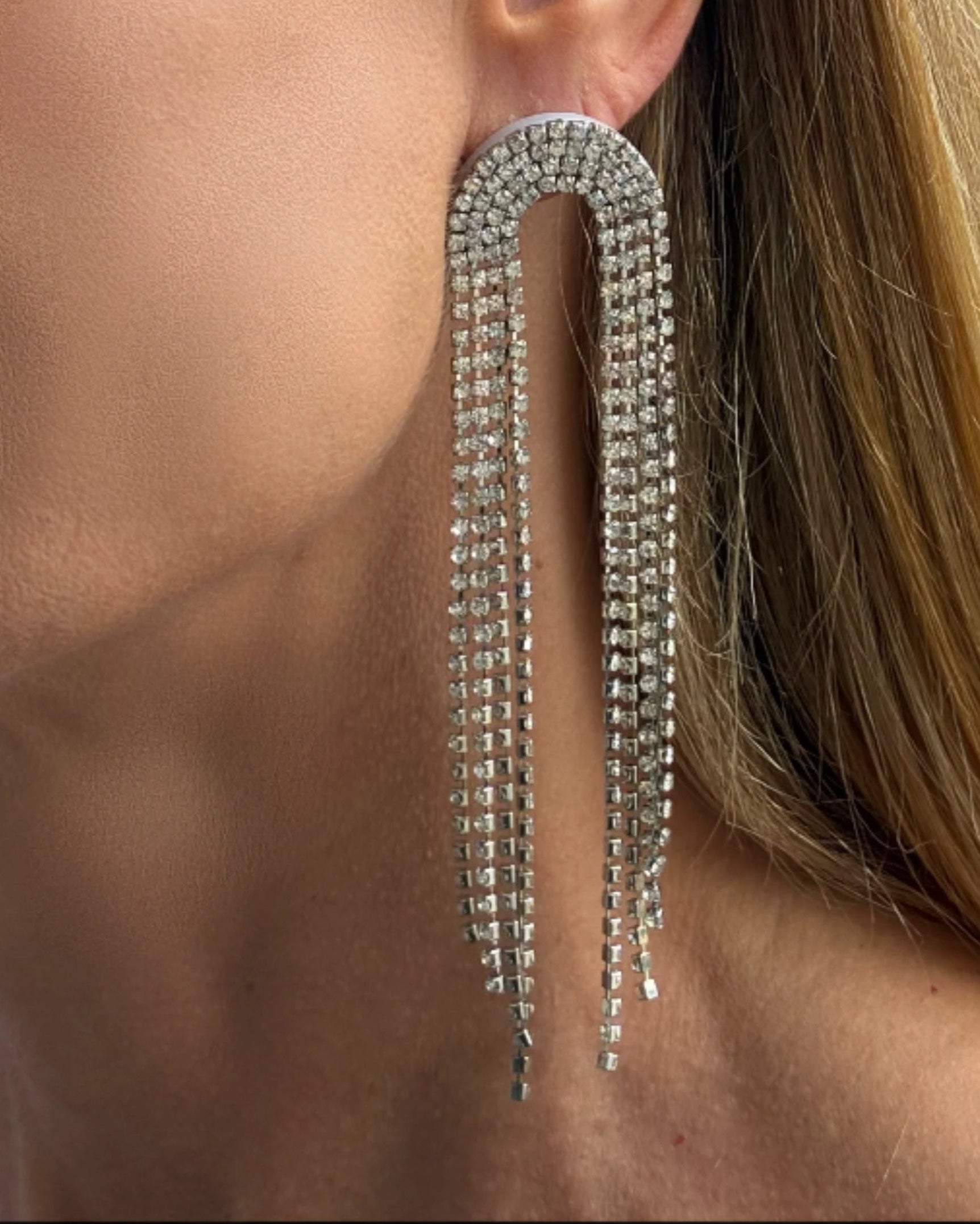 Silver fringe earring worn by a person with blonde hair.