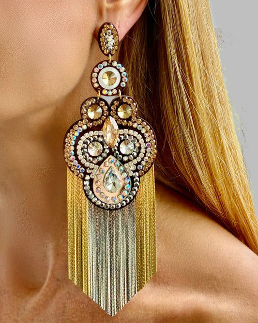Close-up of a person wearing ornate earrings with gold tassels.