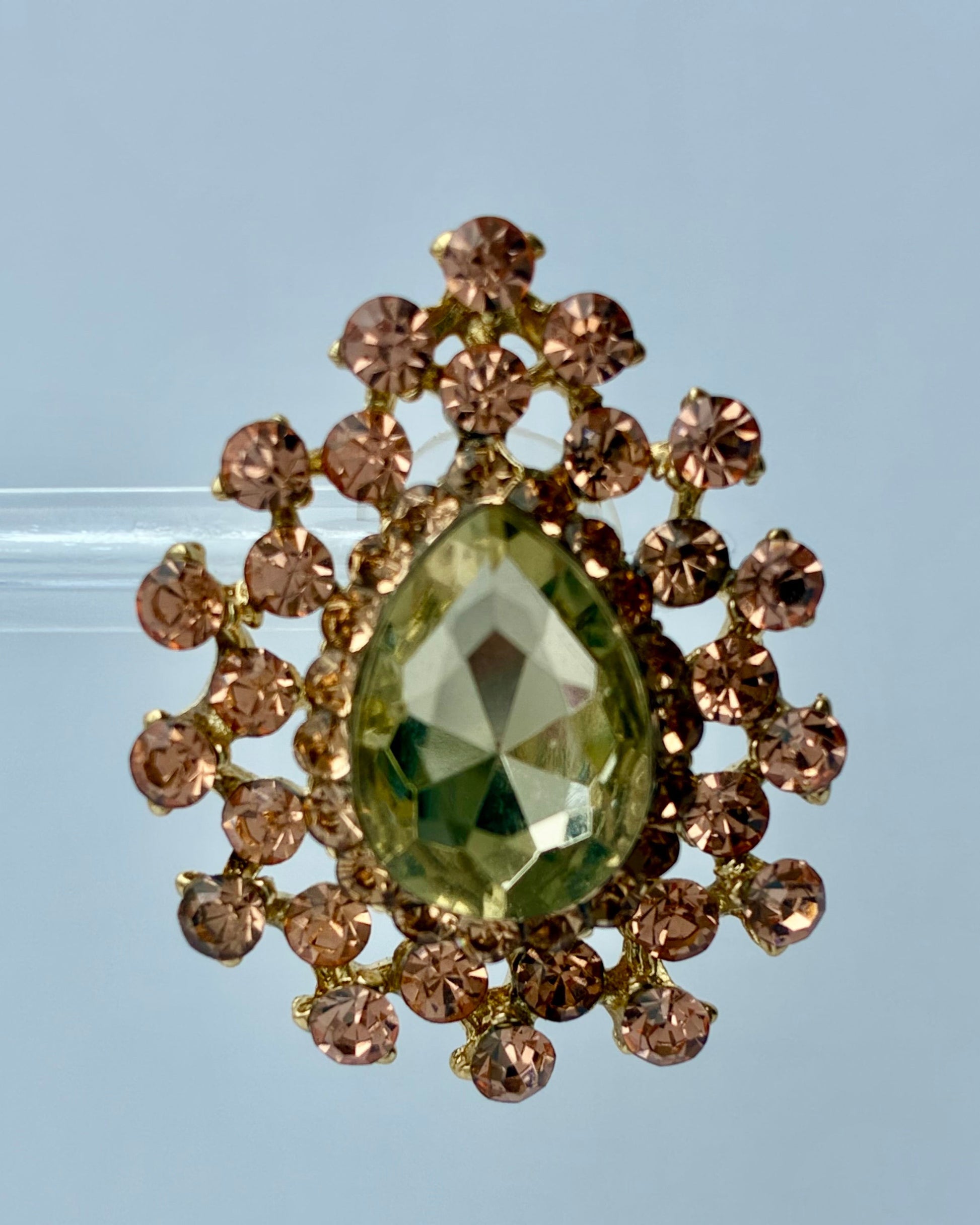 Gold brooch with a green gemstone on a clear background