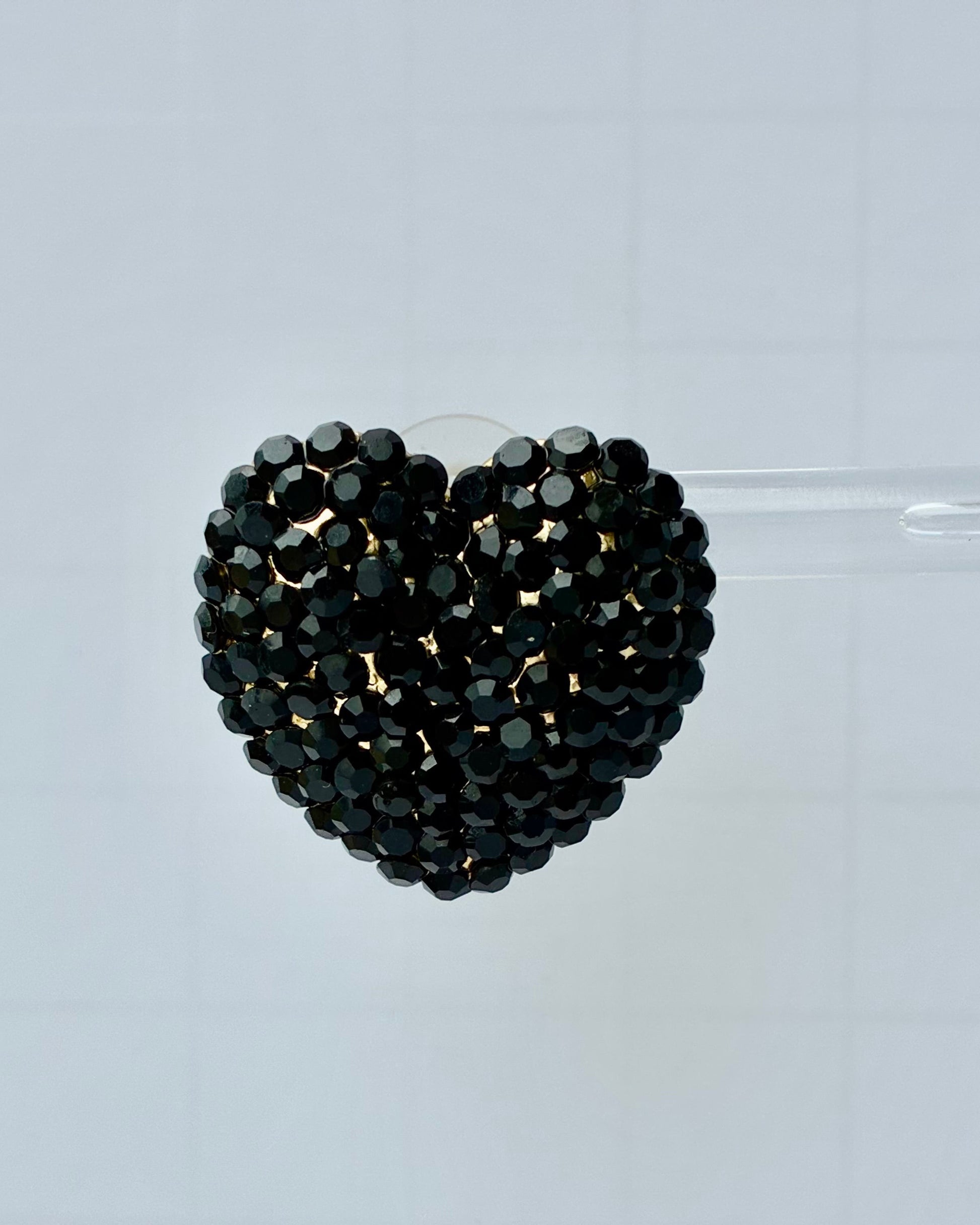 Black beaded heart-shaped object on a clear background