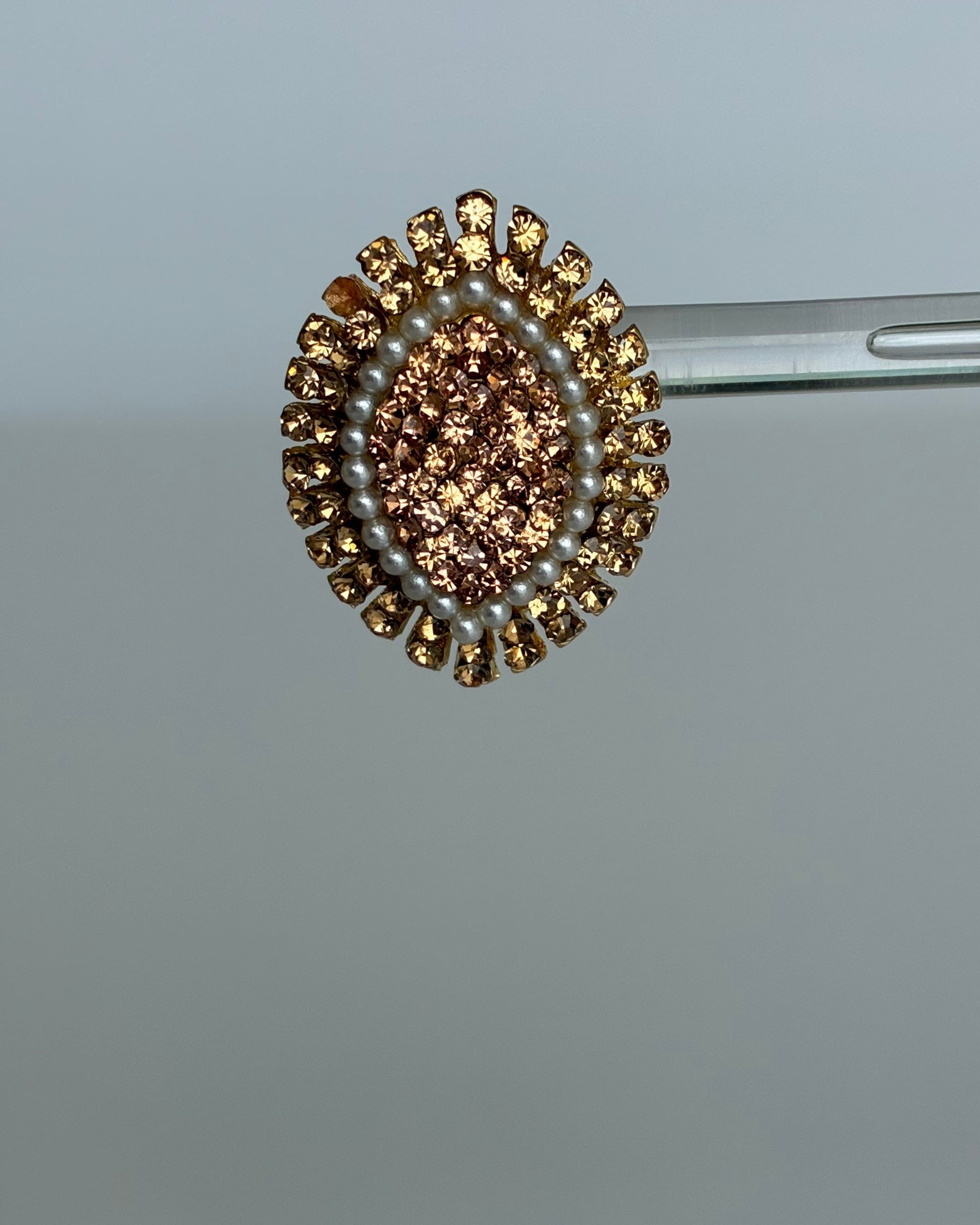 Close-up of a decorative brooch with brown and gold elements on a gray background