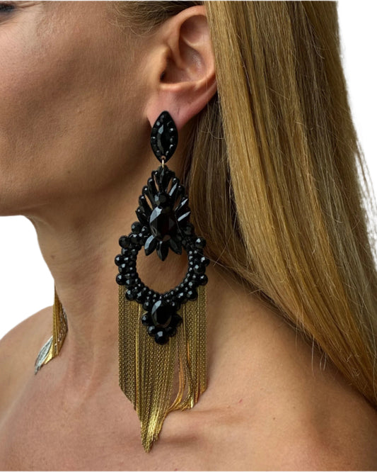 Black and gold earrings worn by a person with a neutral background
