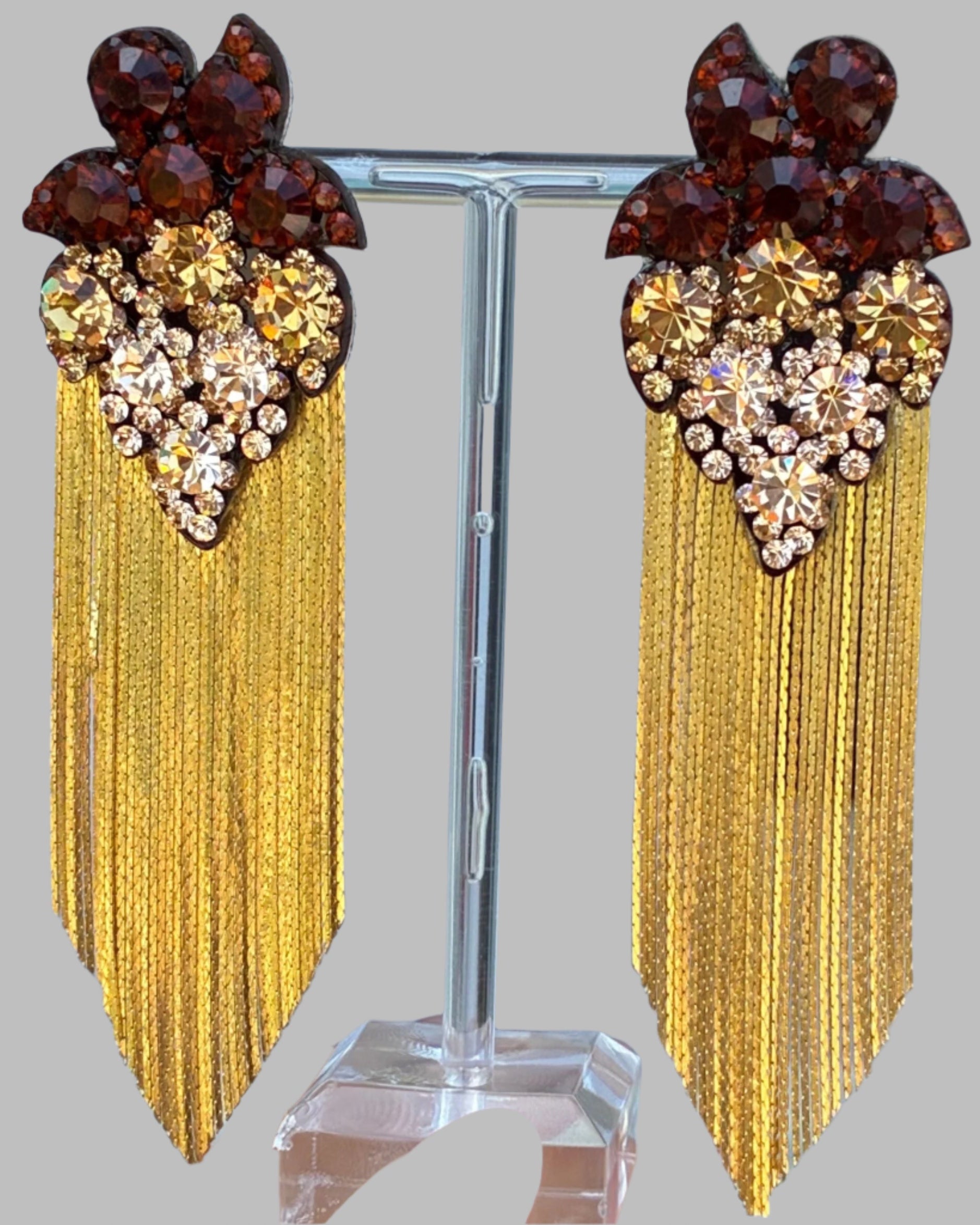Earrings with gold fringe and gemstone accents on a stand