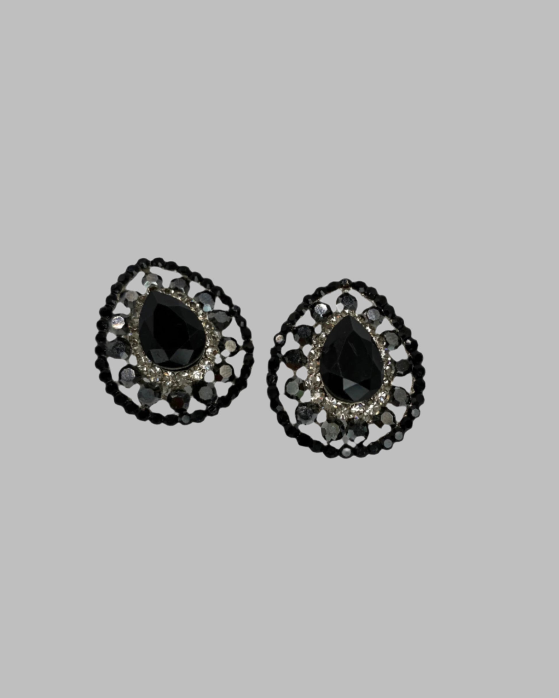 Pair of black teardrop earrings with decorative black and silver frame on a light gray background