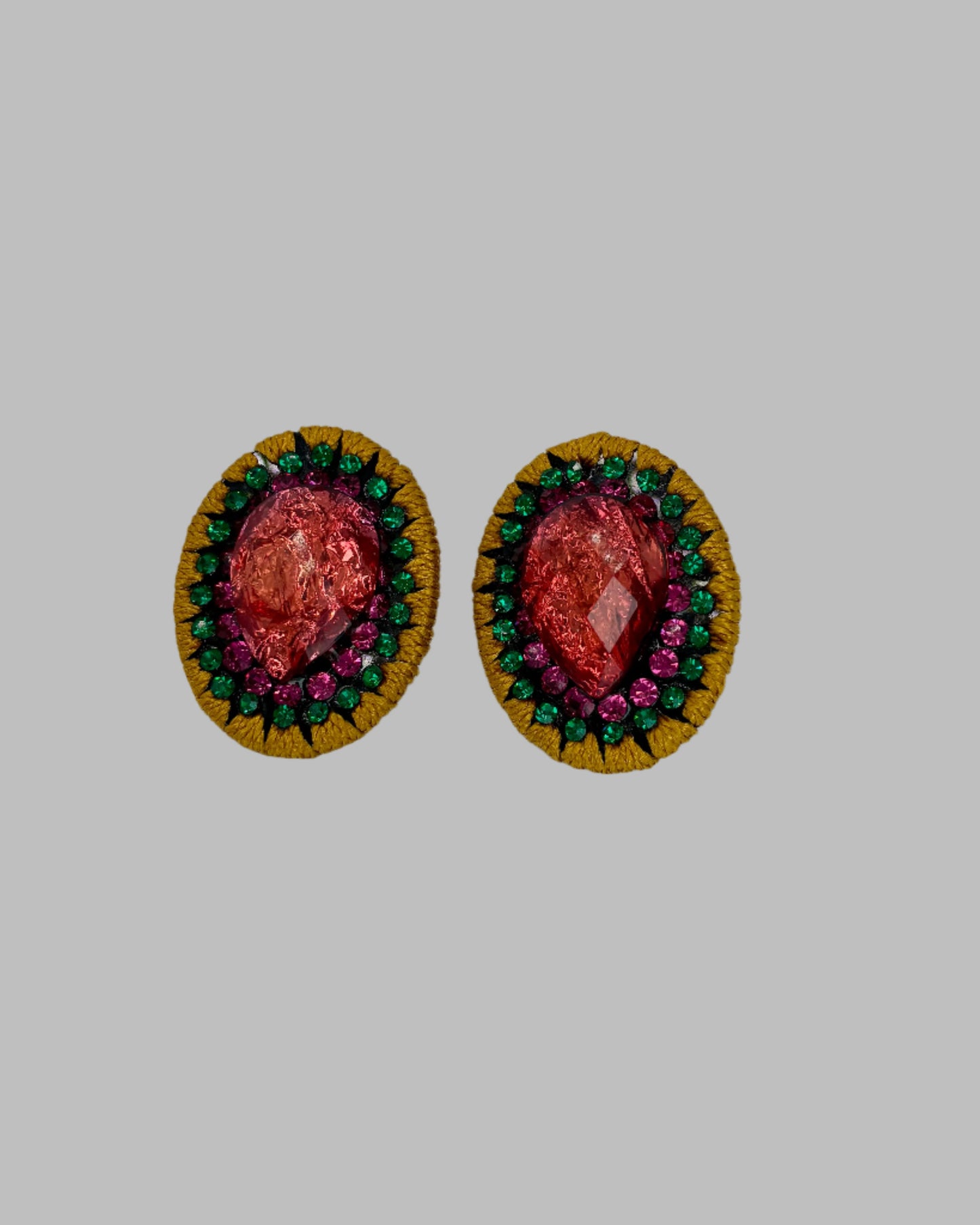 Pair of earrings with colorful gemstones on a light gray background