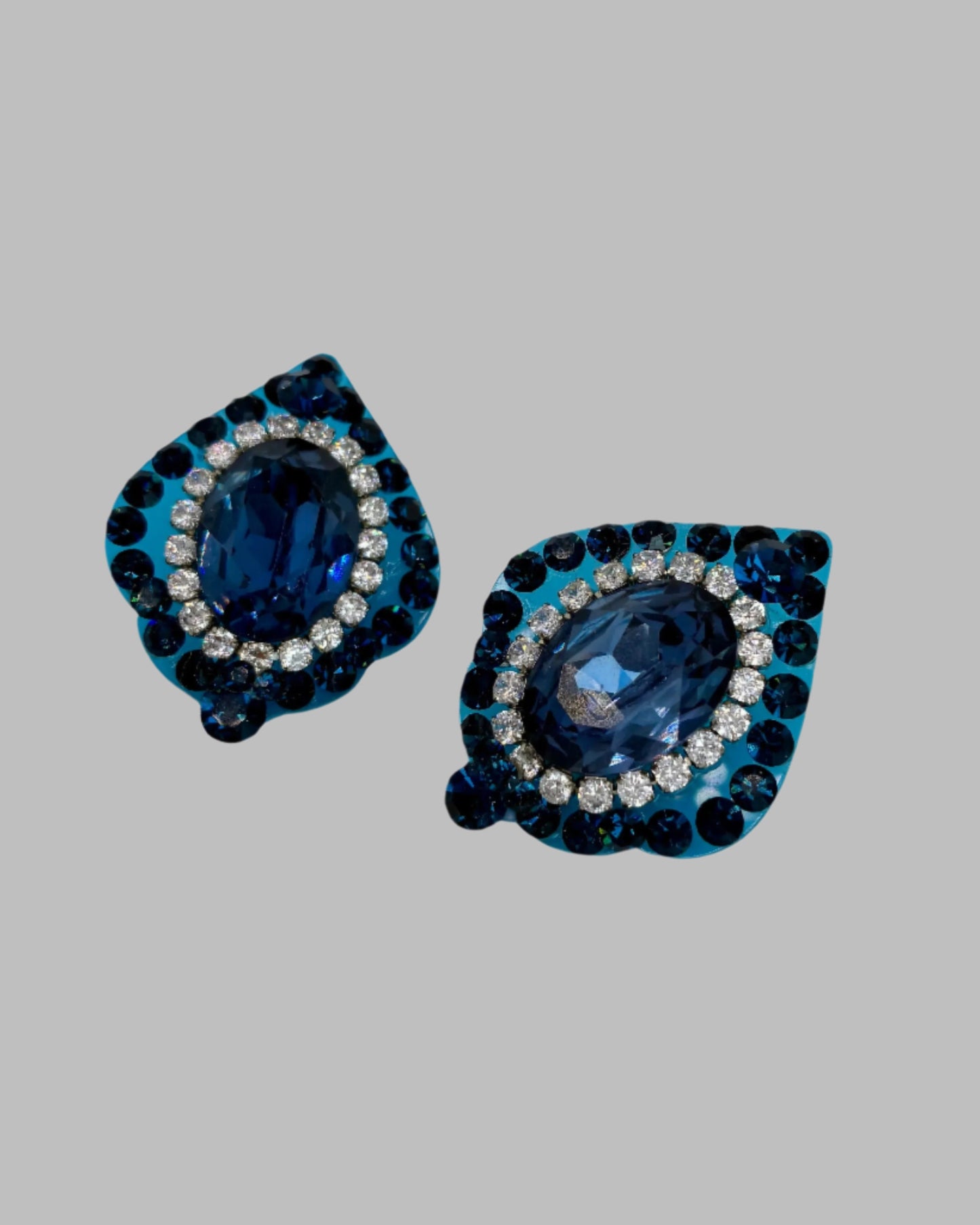 Pair of blue teardrop-shaped earrings with gemstone-like stones on a white background