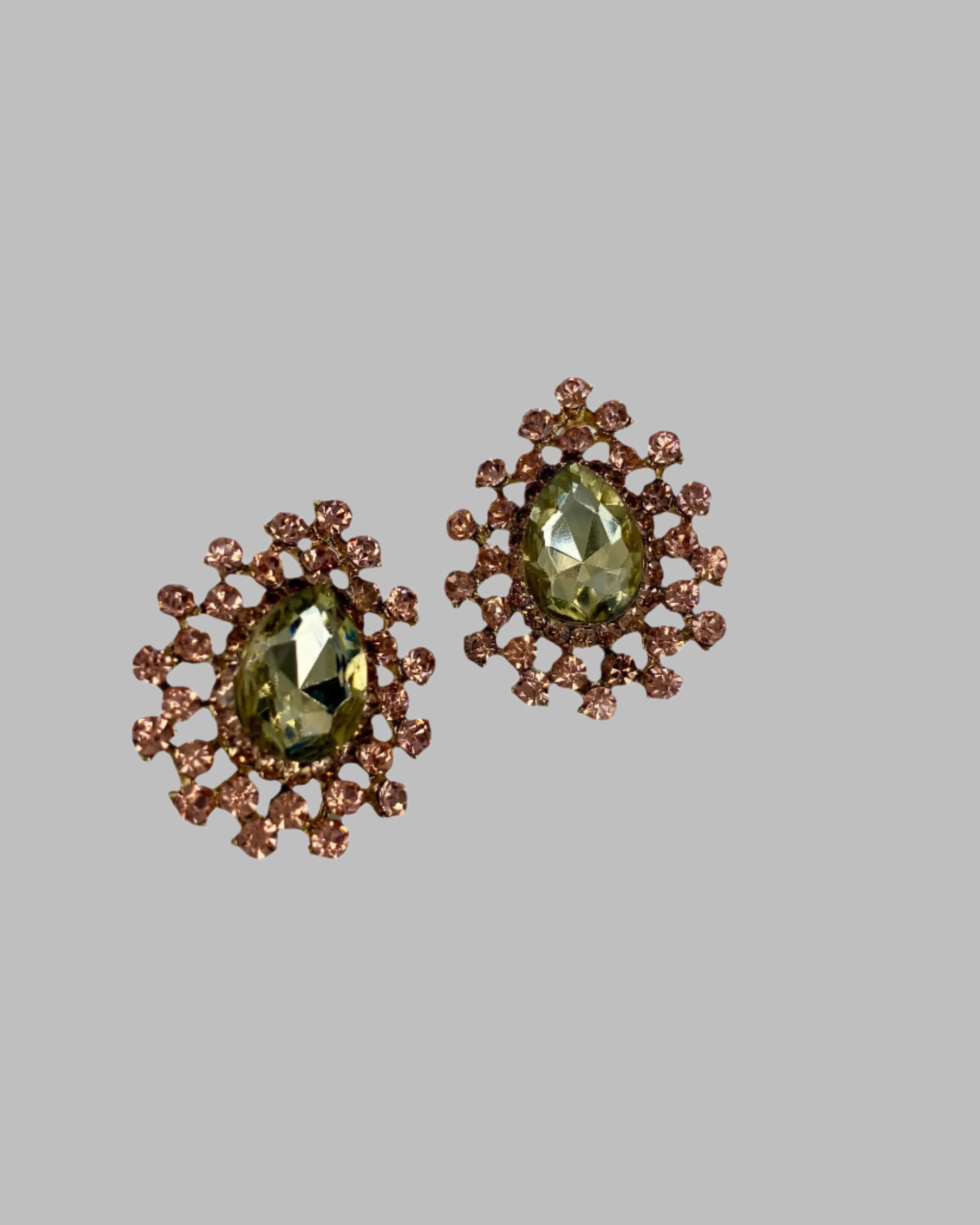 Pair of earrings with green gemstones and brown floral designs on a gray background