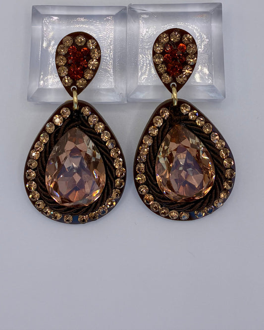 Pair of teardrop-shaped earrings with brown gemstones on a gray background