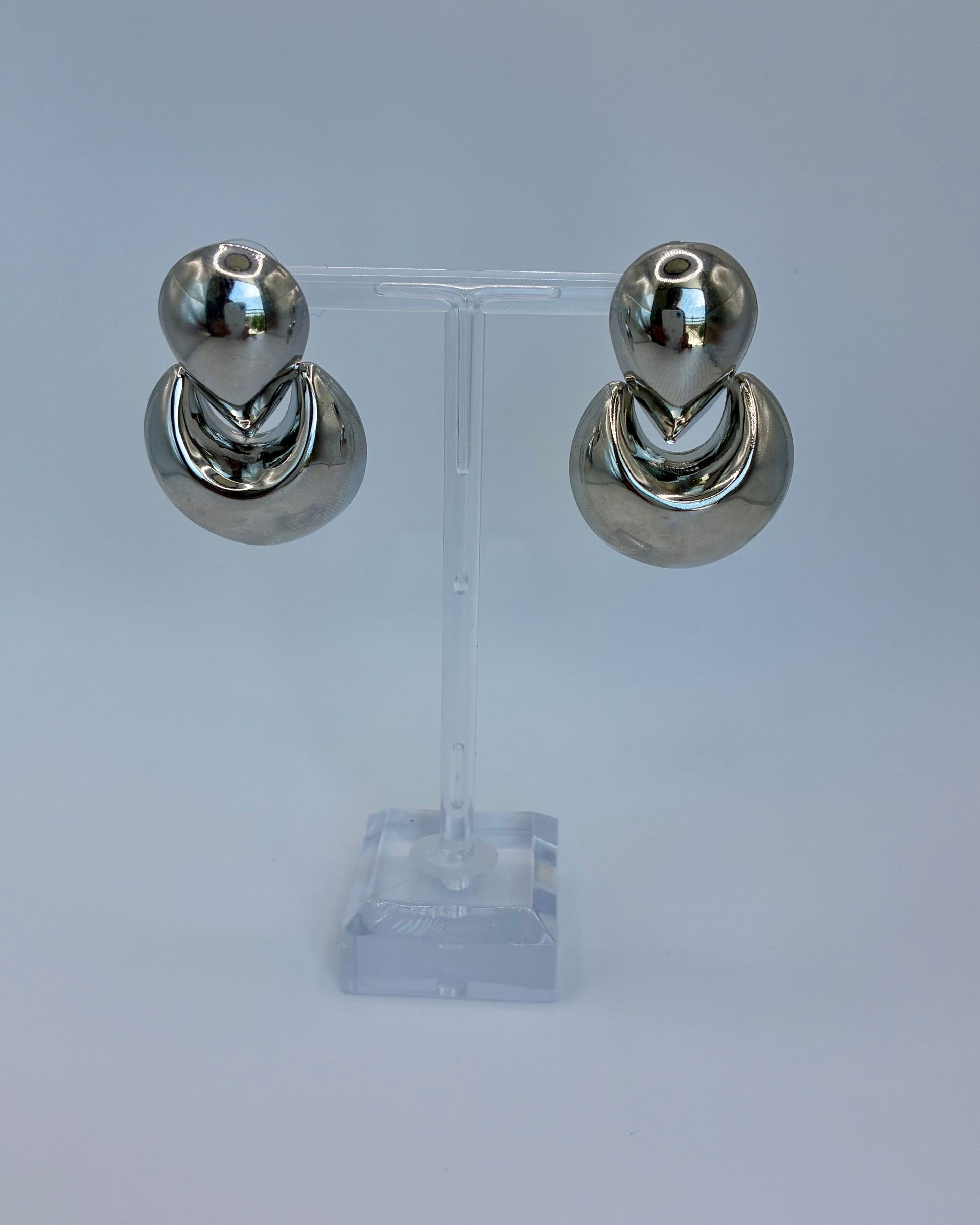 Pair of silver hoop earrings on a clear stand against a light gray background