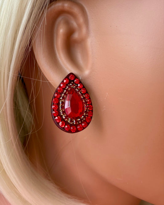 Red teardrop earrings on a mannequin ear with blonde hair.