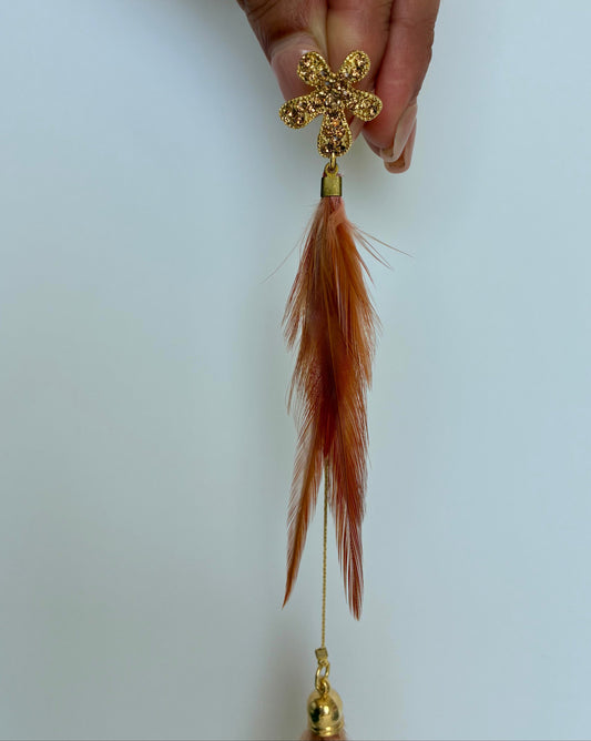 Gold earring with feather on a white background