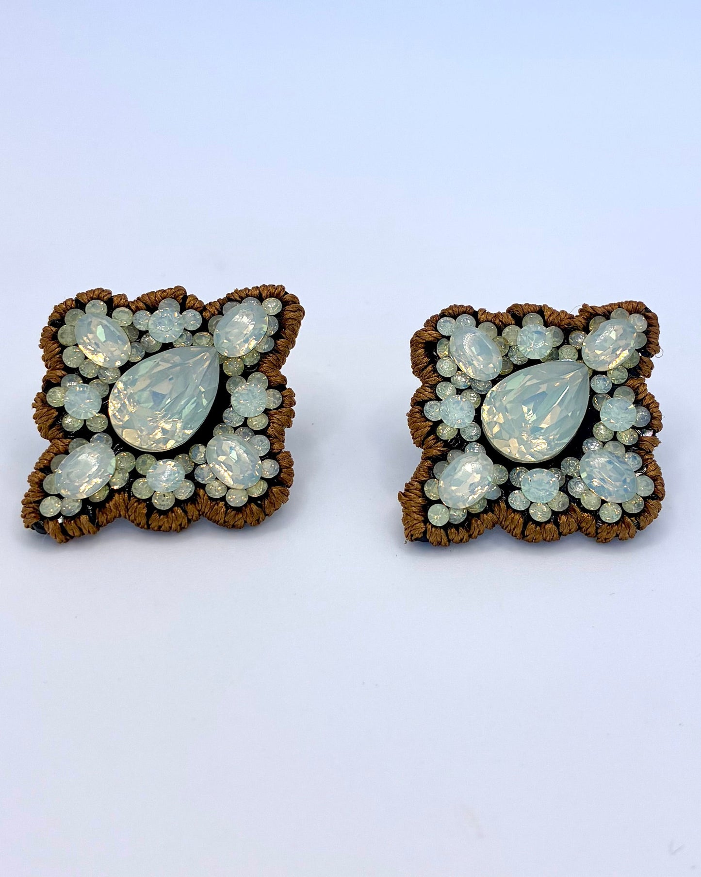 Pair of butterfly-shaped earrings with gemstone-like stones on a light blue background