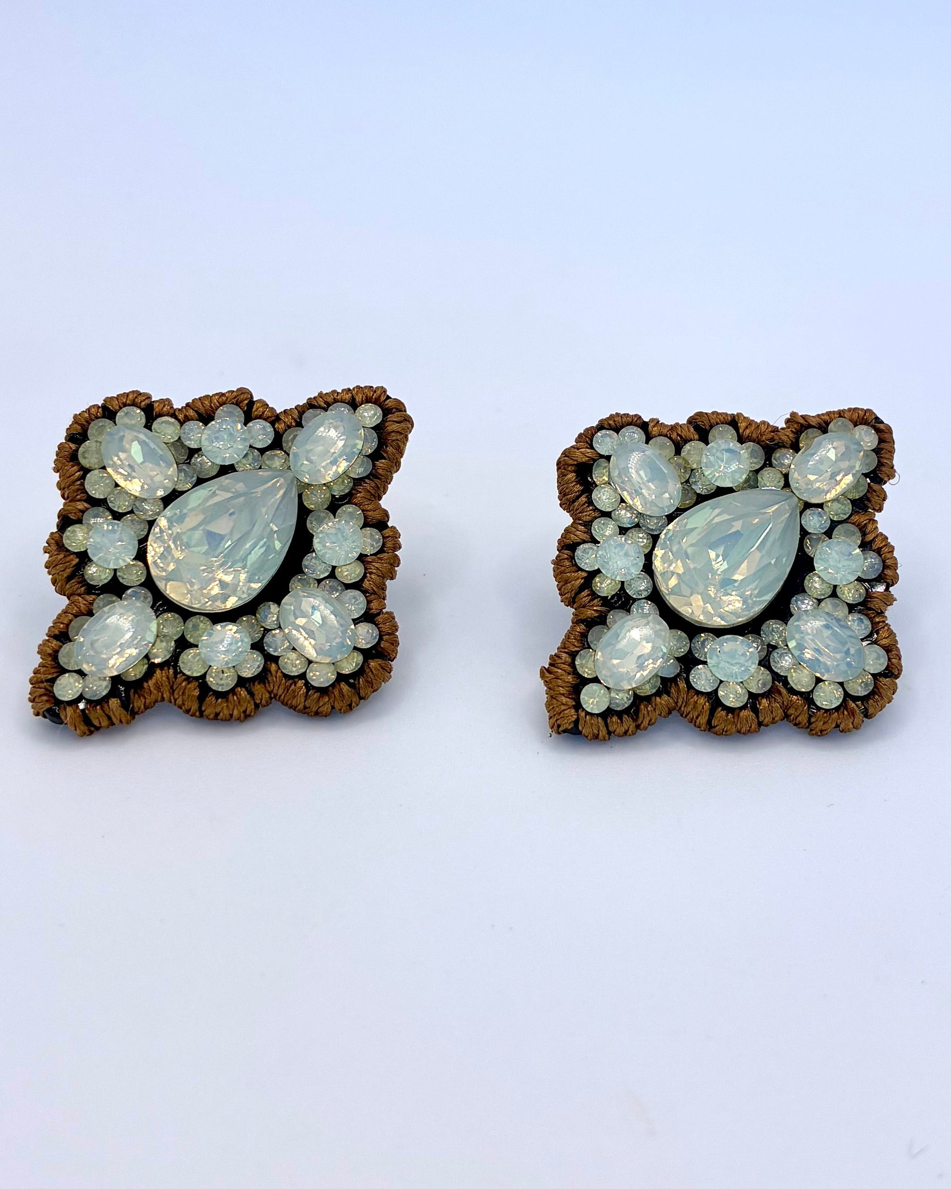 Pair of butterfly-shaped earrings with gemstone-like stones on a light blue background