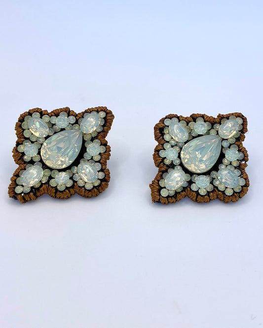 Pair of butterfly-shaped earrings with gemstone-like stones on a light blue background