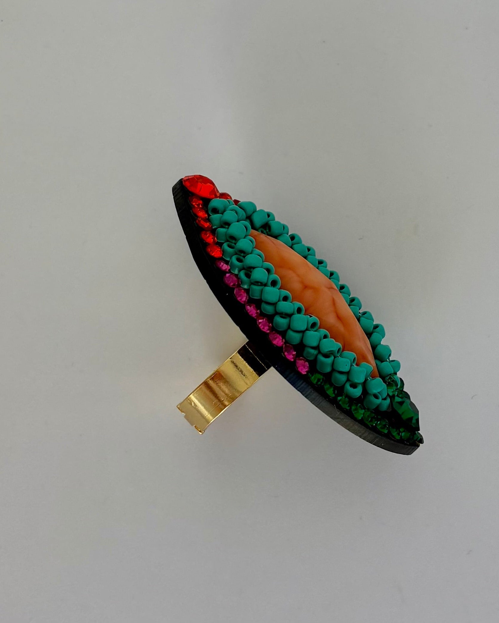 Ring with green bead detailing on a white background