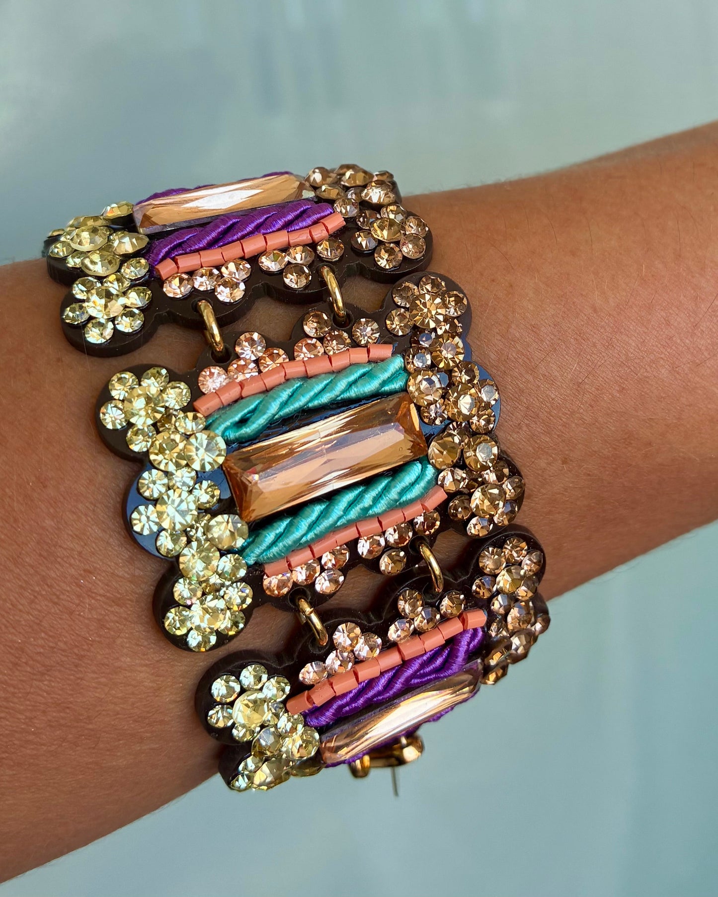 Multicolored bracelet with intricate design on a wrist against a light background